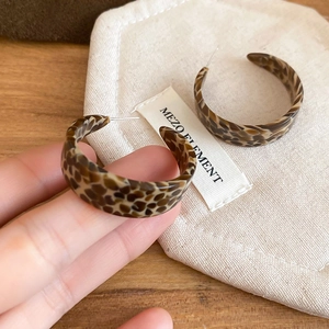Macro shot of tortoiseshell C-shape hoop earrings showing resin texture and leopard pattern