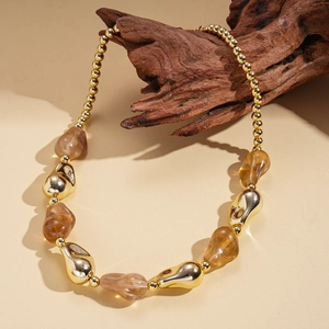 Detail of bohemian acrylic beads and irregular golden metal charms on a sweater necklace