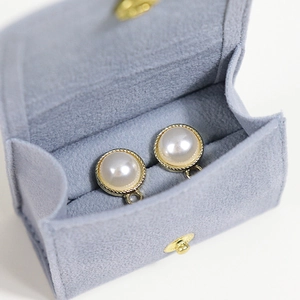 Classic white pearl earrings with gold textured frame in a soft velvet jewelry pouch