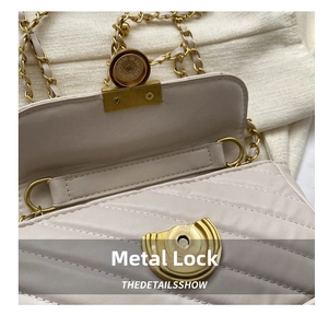 Detailed macro view of gold-tone metal lock and quilted leather stitching on beige handbag