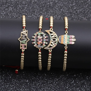 Close-up of gold beaded bracelets with colorful zircon MAMA and MOM charms on a display