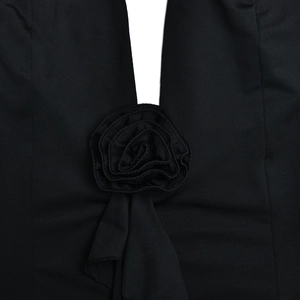 Close-up of a 3D fabric rose detail and ruffled drape on a black bodycon dress