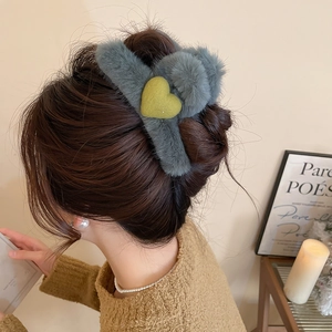 Detail of plush grey claw clip with heart motif styled in long hair for a cozy daily look