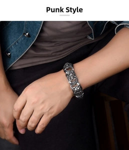 Dettaglio di un bracciale punk vintage con teschi in acciaio al titanio al polso di un uomo