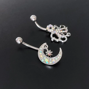 Celestial moon and octopus belly rings with colorful zircon crystals on black background