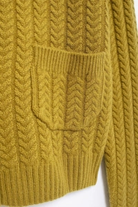 Detailed macro view of mustard yellow cable knit cardigan texture and pocket design