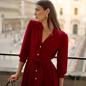Close-up of red elegant dress with gold buttons, tie-waist detail and puff sleeves
