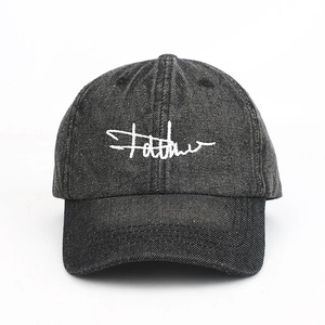 Detail of white linear embroidery on black washed denim baseball cap with six-panel structure