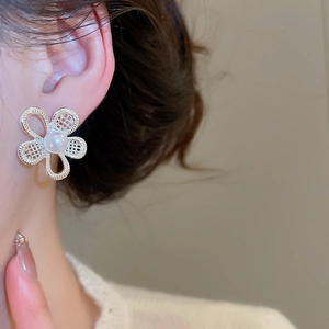 Detailed macro view of hollow flower stud earring with central pearl and mesh petals