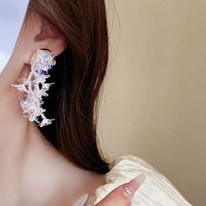 Close-up of oversized pearlescent flower drop earrings on model with beaded petals