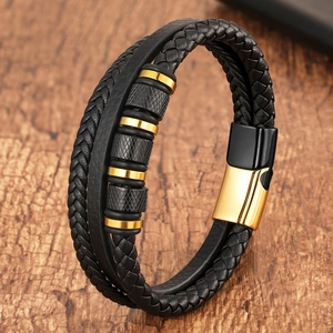 Close-up of woven black leather bracelet with gold magnetic clasp and metal beads