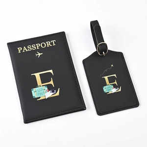 Close-up of black PU leather passport holder and luggage tag set with gold letter E