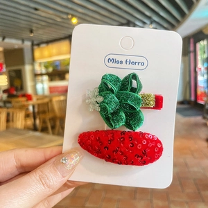 Détail de pinces à cheveux de Noël avec nœud vert scintillant et clip rouge à paillettes