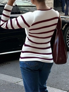 Pull en maille blanc élégant à rayures bordeaux avec un sac à main en cuir assorti dans la rue
