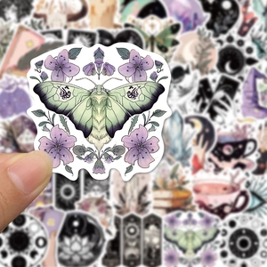 Close-up of a hand holding a purple flower and moth sticker with a matte finish