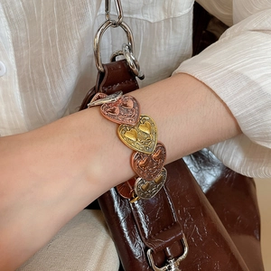 Close-up of tricolor heart-shaped elastic bracelet in gold, silver, and rose gold finishes