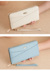 Detail of long zippered leather wallets in beige and blue with wristlet strap