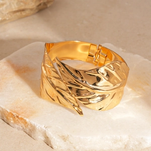 Detailed close-up of golden leaf-shaped bangle with bionic vein textures on stone base