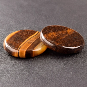 Macro view of two polished tiger eye crystal discs with golden luster and smooth texture