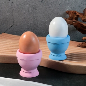 Détail de coquetiers ondulés roses et bleus sur plateau en bois pour le petit déjeuner