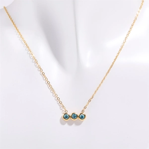 Dettaglio di una collana dorata con tre pendenti rotondi in zirconia blu brillante