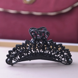Detail of 9cm black metal hair claw clip with intricate hollow patterns and rhinestones