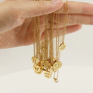 18K gold plated stainless steel 12 zodiac pendant necklaces held in hand on white background