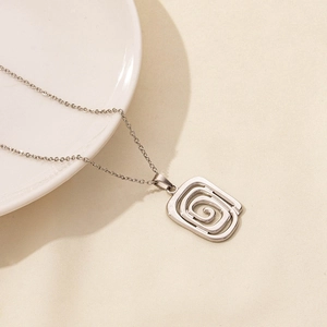 Detailed close-up of a silver rectangular spiral maze pendant on a fine link chain