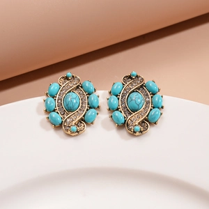 Macro detail of vintage gold-tone earrings with turquoise resin and sparkling crystals