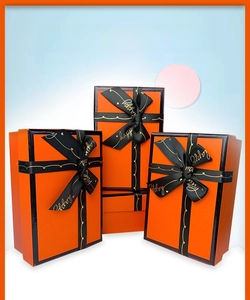 Three-piece orange and black nesting gift boxes with 'Happy' printed satin ribbon