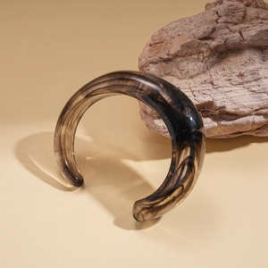 Detail of chunky C-shaped open bangle with smoky brown marble acrylic texture and glossy finish