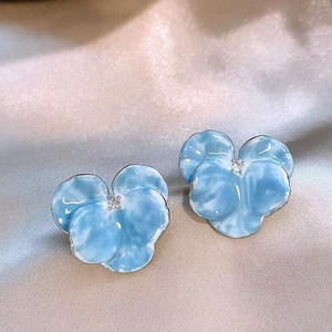 Vue détaillée de boucles d'oreilles fleurs en émail bleu menthe avec un zircon blanc