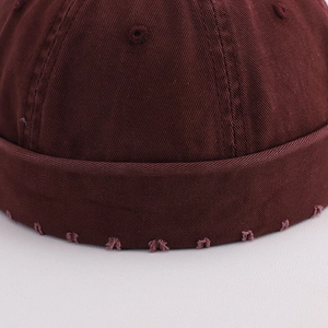 Detail of burgundy docker hat showing twill cotton texture and distressed frayed edges