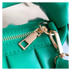 Detailed macro view of green woven leather bag featuring golden zipper and metal hardware