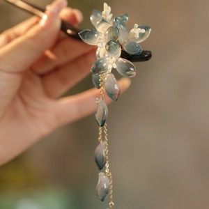 Détail d'épingle à cheveux fleur bleue avec pompons dorés et pétales translucides