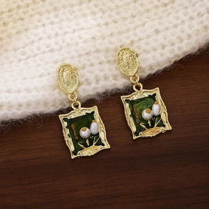 Macro detail of French vintage gold earrings with green enamel and pearl accents