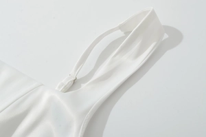 Détail d'une robe en satin blanc avec fines bretelles réglables et coutures précises