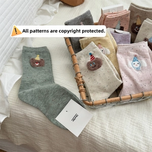 Close-up of cute cartoon bear embroidery on colorful cotton crew socks in a wire basket