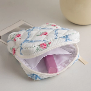Detailed interior of quilted floral makeup bag with pink lipstick showing storage capacity