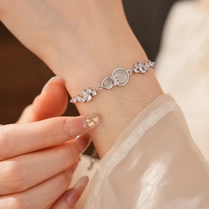 Close-up of a silver bow gourd bracelet with green stones on a model's wrist