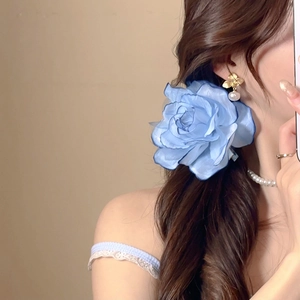 Close-up of a blue fabric flower hair clip with pearl accessories on a model