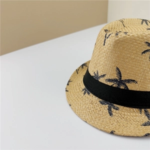 Close-up of straw fedora hat featuring black ribbon and tropical palm tree pattern details