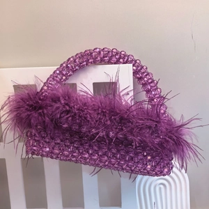 Detail of purple beaded handbag with ostrich feathers hanging on a white chair