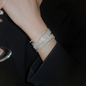 Close-up of sparkling multi-layer faux pearl and diamond cross bracelet on a model