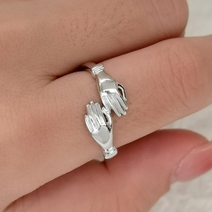 Minimalist S925 sterling silver hugging hands open ring shown on a finger