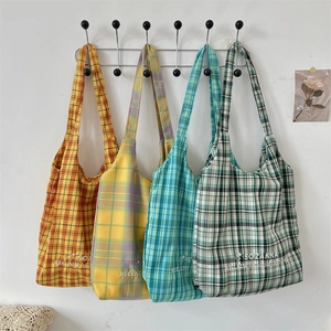 Detail of colorful plaid canvas tote bags with SOZAKKA embroidery hanging on a wall