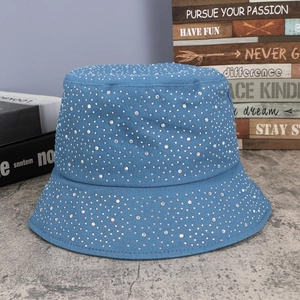 Close-up of blue denim bucket hat with shiny rhinestones on a textured surface
