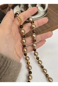Détail du collier en perles d'œil de tigre avec fermoir doré et tons bruns chauds