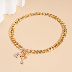Detail shot of golden Cuban link necklace with diamond-encrusted lock and key pendants
