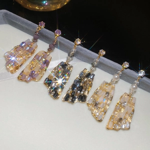 Detail of geometric square crystal earrings with silver needles and gold-tone metal frames